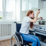 A girl sitting on a wheelchair cooking something
